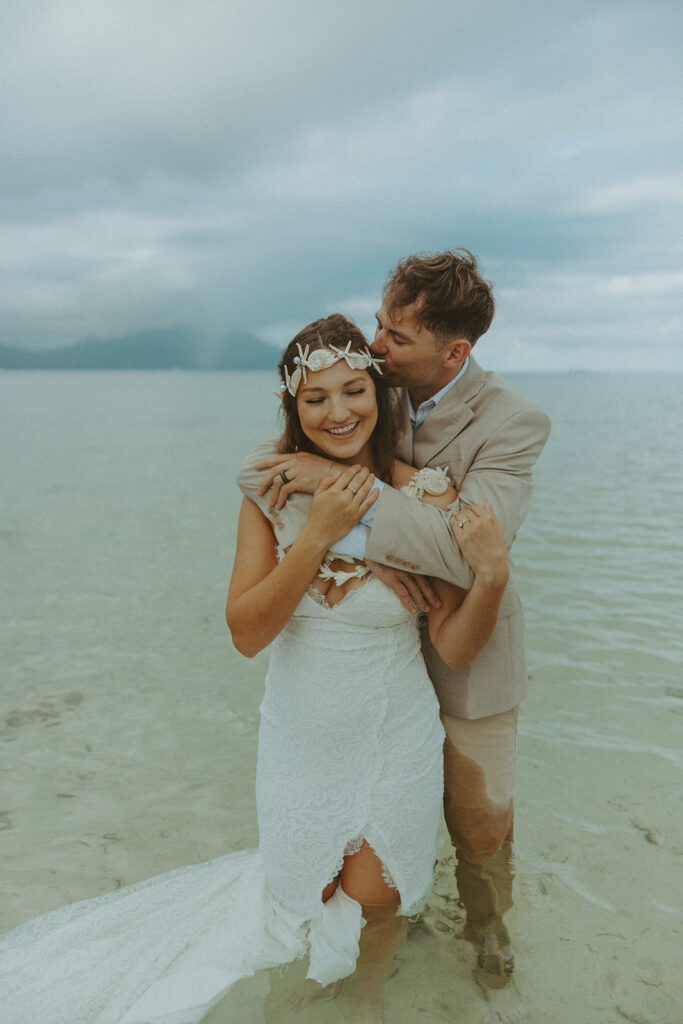 Bride and groom standing in shallow ocean water during a beach wedding ceremony