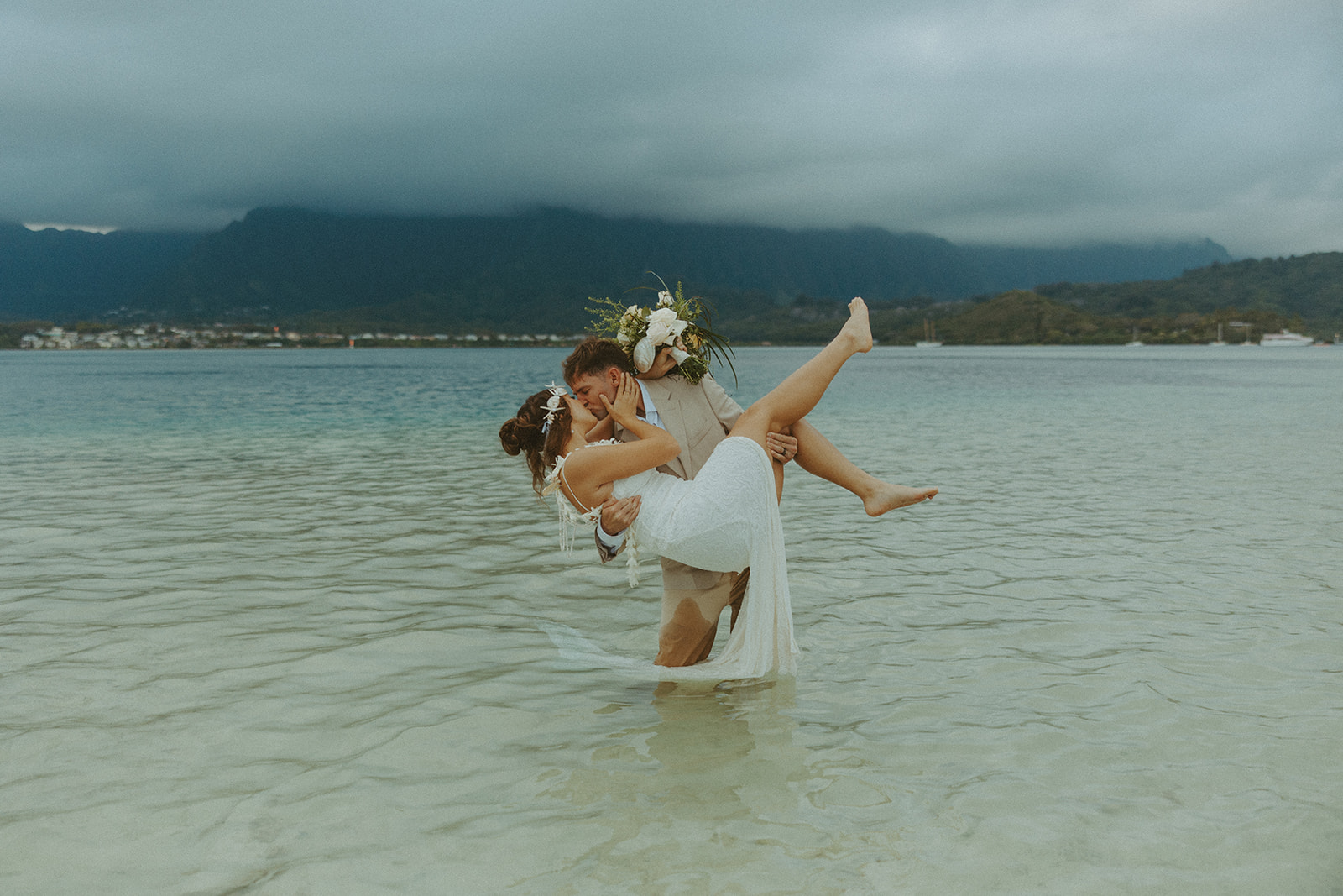 Bride and groom standing in shallow ocean water during a beach wedding ceremony