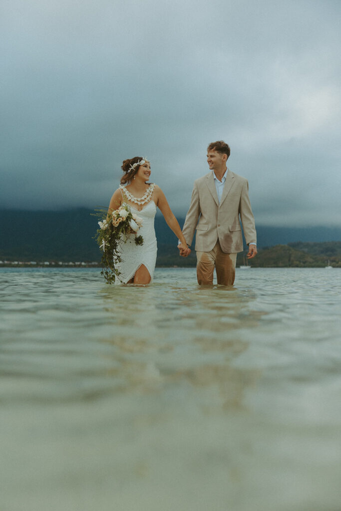 Bride and groom standing in shallow ocean water during a beach wedding ceremony