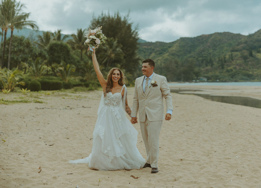 Bride and groom holding hands during an intimate beach wedding on Kauai’s north shore.
