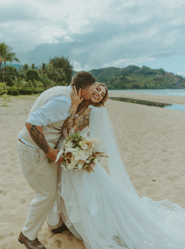Newlyweds walking along a scenic coastal overlook in Kauai at sunset.