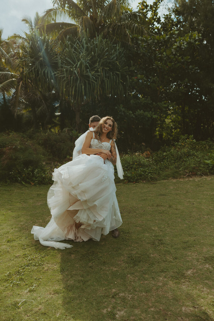 Newlyweds walking along a scenic coastal overlook in Kauai at sunset.