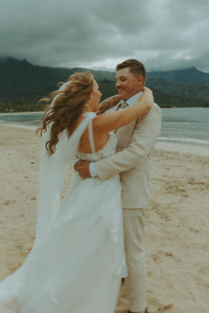 Bride and groom holding hands during an intimate beach wedding on Kauai’s north shore.

