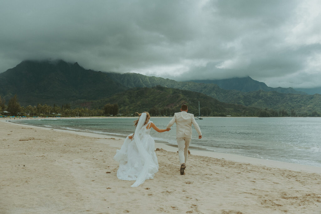 Bride and groom holding hands during an intimate beach wedding on Kauai’s north shore.
