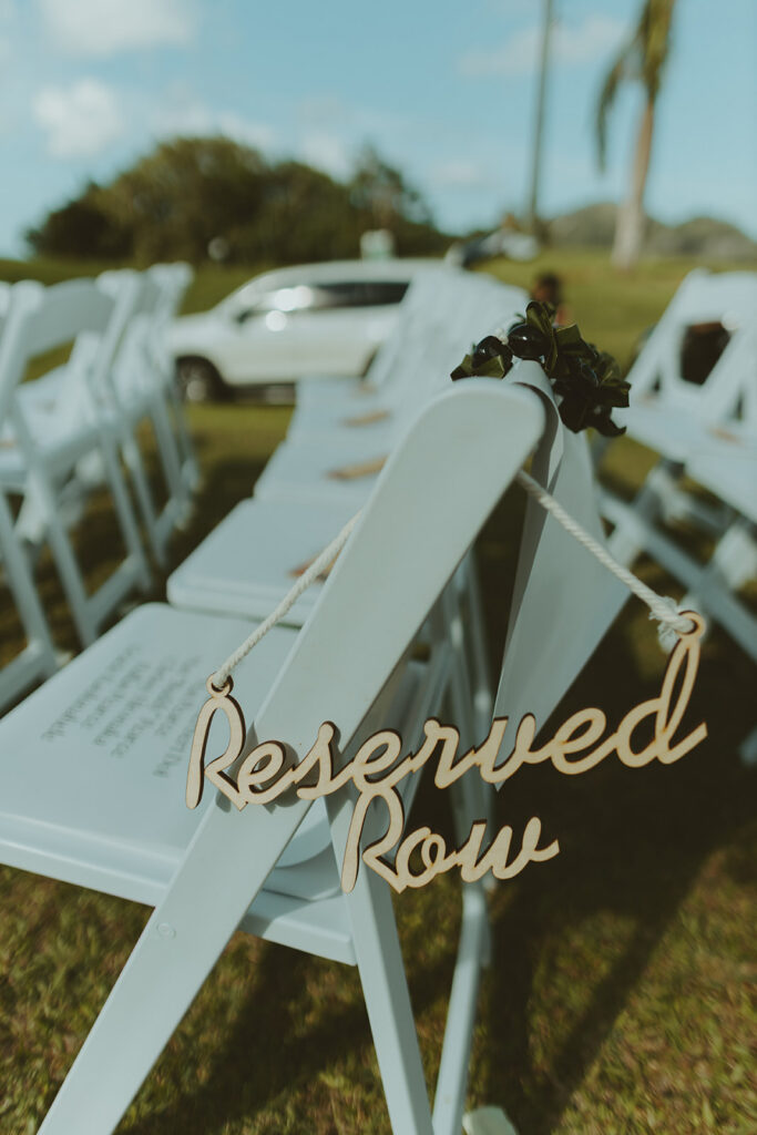 Outdoor wedding ceremony setup with white chairs and floral ceremony arch