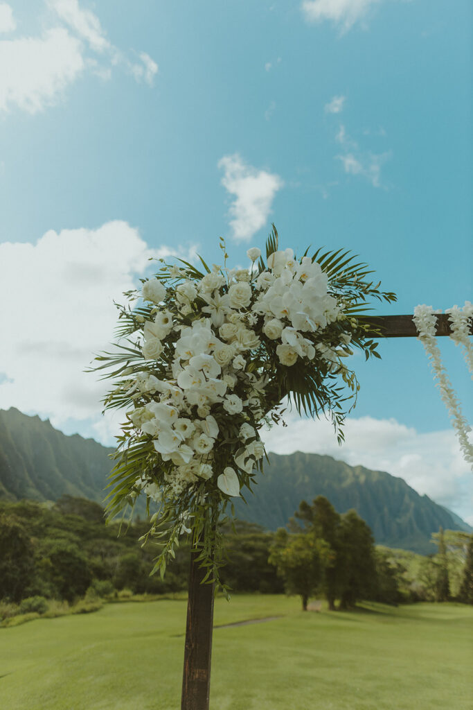 Elegant outdoor wedding ceremony setup with mountain views and floral arch
